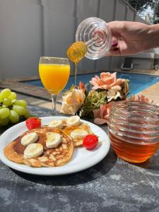 a plate of pancakes with fruit and a glass of orange juice at Hotel Dan Inn Araraquara in Araraquara