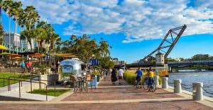 personas caminando y montando bicicletas en una acera junto a un río en Boho Tampa Townhouse - Pool, Gym, Arcade, en Tampa