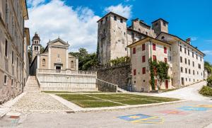 a castle on a hill with some buildings and grass at BORGO VERTICALE Luxury Apartments in Feltre