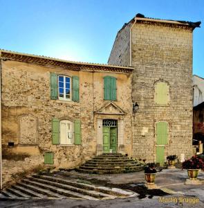 an old stone building with green doors and stairs at La tour de Pezene in Anduze