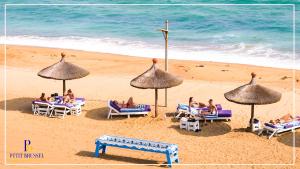 a group of people sitting on a beach with umbrellas at Hotel Petit Brussel in Lomé