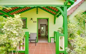 une maison verte avec une pergola verte dans l'établissement Hôtel Bambou & Spa, à Les Trois-Îlets