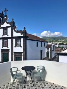 a patio with two chairs and a table on a roof at Charme do Largo - Apartamento in Lagoa