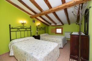 GallocantaにあるCasas rurales LA LAGUNA y LA BUHARDILLA DE LA LAGUNAの緑の壁と木製の天井が特徴のベッドルーム1室(ベッド2台付)