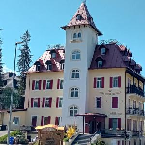 a large white building with a clock tower at Hotel Regina del Bosco in Ronzone