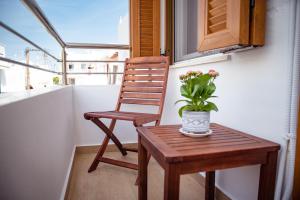 a chair and a table with a vase of flowers on a balcony at Anasasmos House in Naxos Chora
