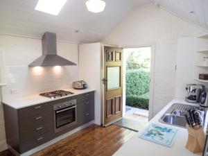 a kitchen with a stove top oven next to a sink at Cottage 79 in Orange