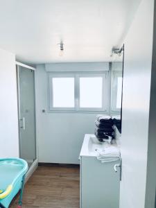 ein weißes Bad mit einem Spiegel und einem blauen Stuhl in der Unterkunft La villa des retrouvailles in Ploufragan