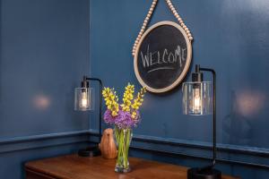 a table with a vase of flowers and a mirror at By the Side of the Road Inn & Cottages in Harrisonburg