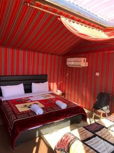 um quarto com uma cama com uma parede vermelha em وادي رم يوسف em Wadi Rum