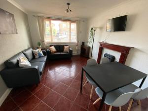a living room with a couch and a table at Birch Avenue House, entire house with 4 bedrooms, free parking, free WI-FI, Smart TV, washing machine, easy access to M1 in Ilkeston
