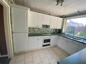 a kitchen with white cabinets and a sink at Birch Avenue House, entire house with 4 bedrooms, free parking, free WI-FI, Smart TV, washing machine, easy access to M1 in Ilkeston