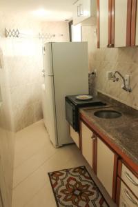 a small kitchen with a refrigerator and a sink at Belíssimo Flat em Pinheiros in Sao Paulo