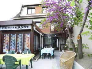 a restaurant with tables and chairs and a tree with purple flowers at Hotel Paris Star in Villejuif