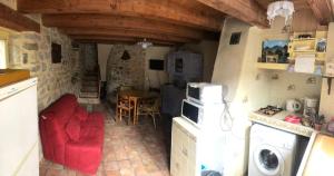 a small kitchen with a red couch and a table at maison vacances in Quézac
