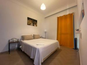 1 dormitorio con cama blanca y cortina naranja en Séjour sable et mer: Jardin privé, Plage à 2 pas en Skhirat