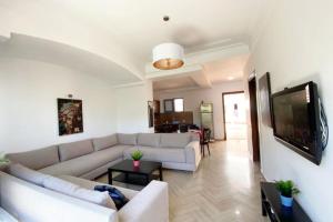 uma sala de estar com um sofá e uma televisão de ecrã plano em Appartement FONTAINE em Skhirat
