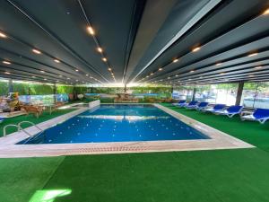una piscina en un edificio con suelo verde y sillas en Kadeer Hotel, en Alanya