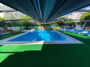una piscina con sillas azules y un edificio en Kadeer Hotel, en Alanya