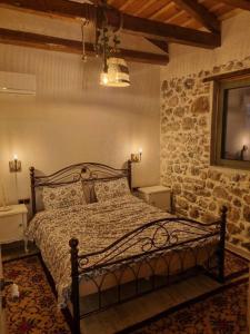 a bedroom with a bed and a stone wall at Stone House - Πέτρινο Σαλέ in Alíartos