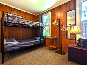 a bedroom with bunk beds in a wooden wall at Bunk & Brew Historic Lucas House - Hostel in Bend