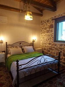 a bedroom with a bed with a stone wall at Stone House - Πέτρινο Σαλέ in Alíartos