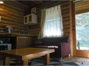 sala de estar con sofá, mesa y ventana en Karuizawa Sunny Village - Vacation STAY 57947v en Karuizawa