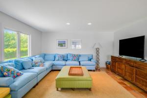 uma sala de estar com um sofá azul e uma televisão de ecrã plano em Meadow Beauty em Westhampton Beach