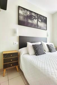 a bedroom with a white bed with a black headboard at HOSTAL RIGAU in Sant Feliu de Guixols