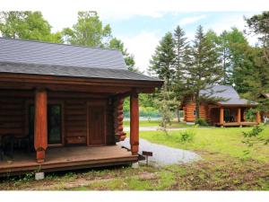 uma cabana de madeira com um alpendre e uma casa em Karuizawa Sunny Village - Vacation STAY 57953v em Karuizawa