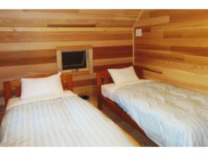 two beds in a room with wooden walls at Karuizawa Sunny Village - Vacation STAY 57953v in Karuizawa
