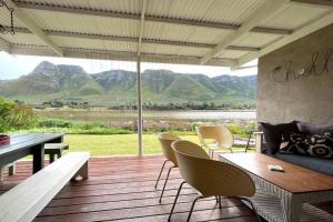 a porch with a table and chairs and a view of mountains at Tranquility in Hermanus
