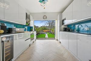 a kitchen with white cabinets and a view of a yard at Wembley Luxury Residence- Opulence House in London