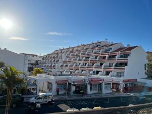 een groot gebouw met een parkeerplaats ervoor bij La casita de la piscina in Adeje