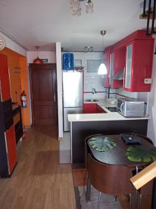 a kitchen with red cabinets and a table in it at Apartamento La Riberuca in Suances