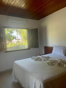 um quarto com uma cama branca e uma janela em Pousada Pratigi em Ituberá