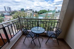 balcón con mesa, sillas y vistas en Luxurious-2 bedroom Furnished Apartment, en Nairobi