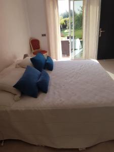 - un grand lit avec des oreillers bleus dans une chambre dans l'établissement Villa AKWABA, à Aït Ourir