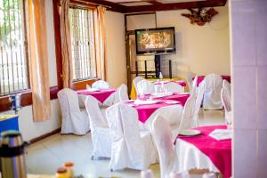 a dining room with pink tables and white chairs at MBEYA PARADISE INN in Mbeya