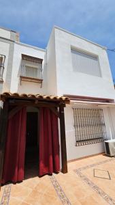 a white house with red curtains in front of it at Apartamento Trajano in Santiponce