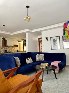 een woonkamer met een blauwe bank en een tafel bij Mid-Century 1 bedroom apartment in Nairobi