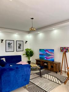 een woonkamer met een blauwe bank en een tv bij Mid-Century 1 bedroom apartment in Nairobi