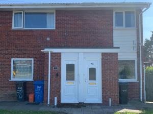 a brick house with a white door and two trash cans at SUNNY PRESTATYN APARTMENT in Prestatyn