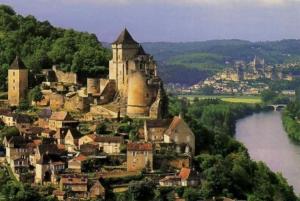 a castle on a hill next to a body of water at Maison 6km de Sarlat piscine chauffée et jacuzzi in Saint-Vincent-le-Paluel
