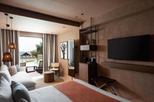 a hotel room with a bed and a flat screen tv at Domes of Corfu, Autograph Collection in Glyfada