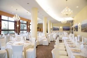 a banquet hall with white tables and chairs and chandeliers at Hotel Cosmopol in Laredo