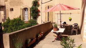 eine Terrasse mit einem Tisch, einem Sonnenschirm und einem Tisch mit Pflanzen in der Unterkunft Hôtel Du Cours in Pertuis