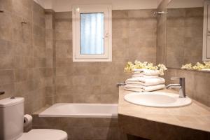 a bathroom with a sink and a tub and a toilet at Nest Aegina Apartments in Perdika