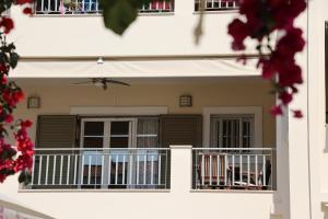a white house with a balcony and red flowers at Nest Aegina Apartments in Perdika