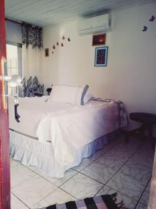 a bedroom with a large bed with white sheets at Suítes Novo Amanhecer in Sao Jorge
